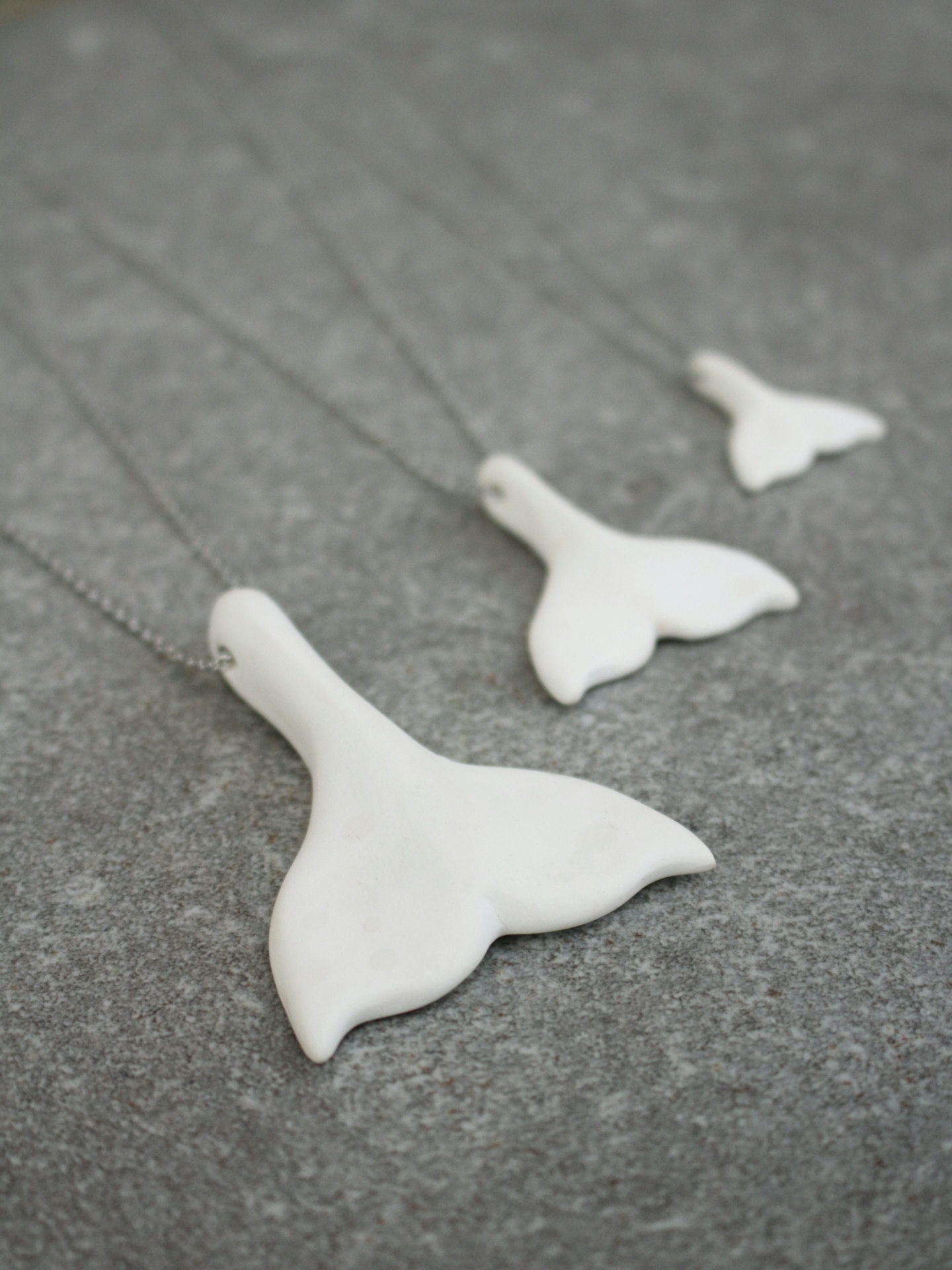 Whale fluke necklaces, hand made out of porcelain.